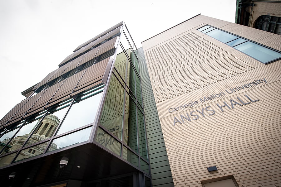 Looking up at ANSYS Hall with a reflection of the Hamerschlag tower in the window