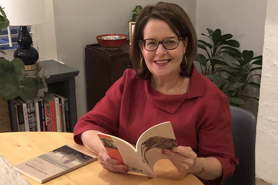 Cynthia Lamb sitting at table holding a book open