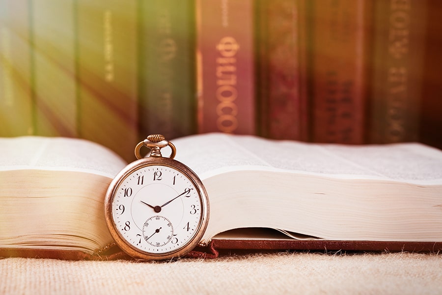 a pocket watch next to an open book