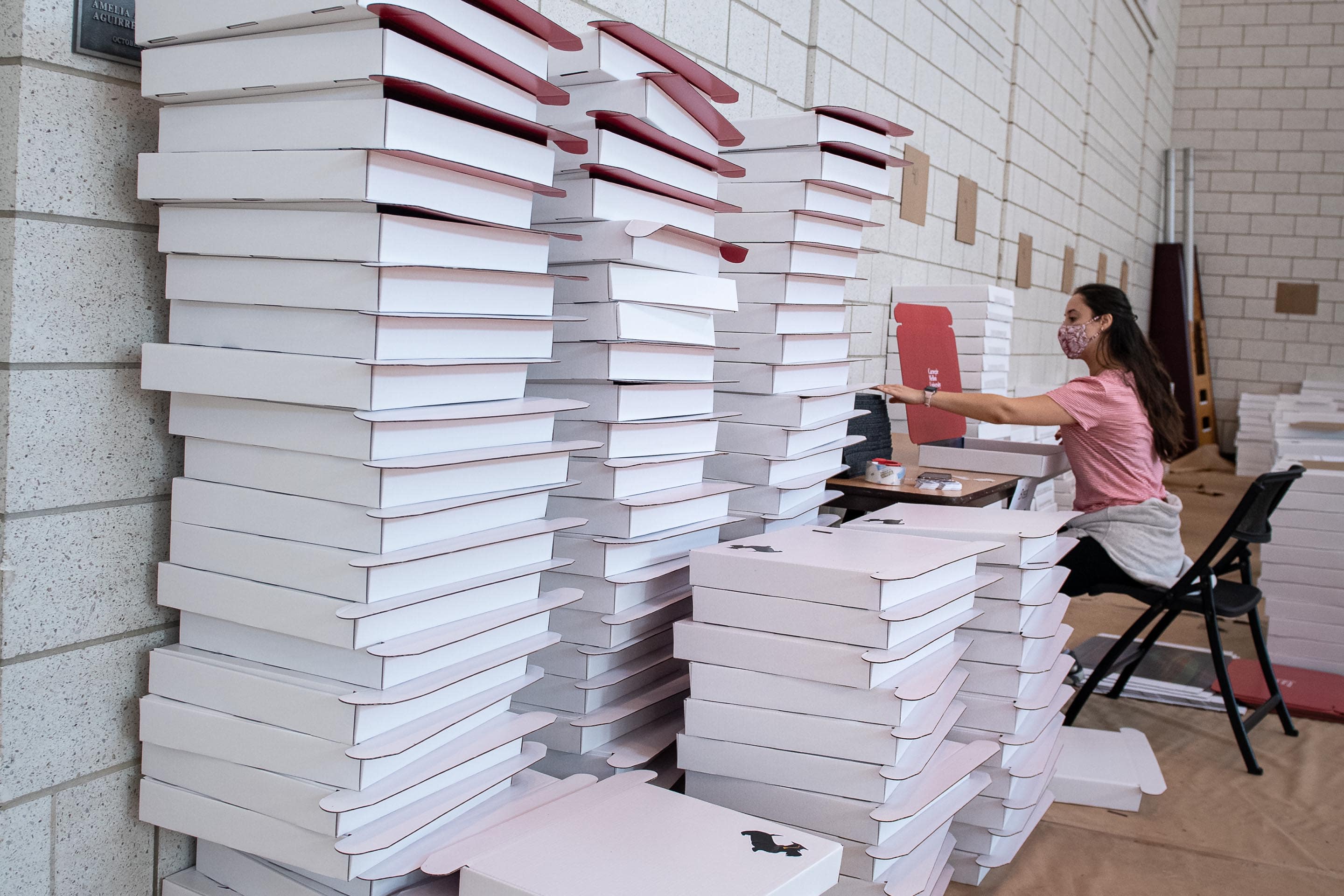 Image of girl assembling diploma box next to stacks of flat white boxes
