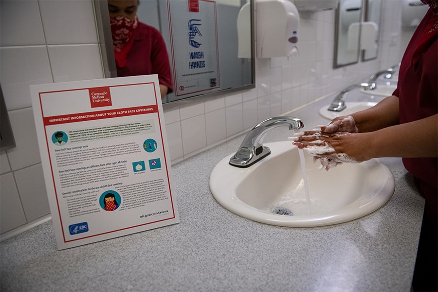 image of someone washing their hands in a bathroom sink with signage nearby