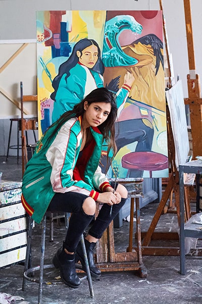 Sachi Shah sitting on a stool in her art studio