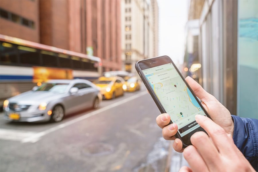 mobile phone in someone's hand with cars on street in background