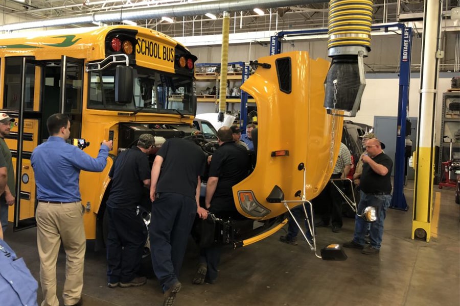 people working on school bus with hood open