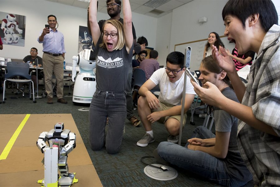 Students cheering alongside robot