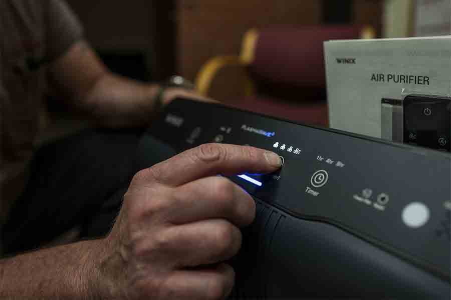 Image of someone pushing a button on the air purifier