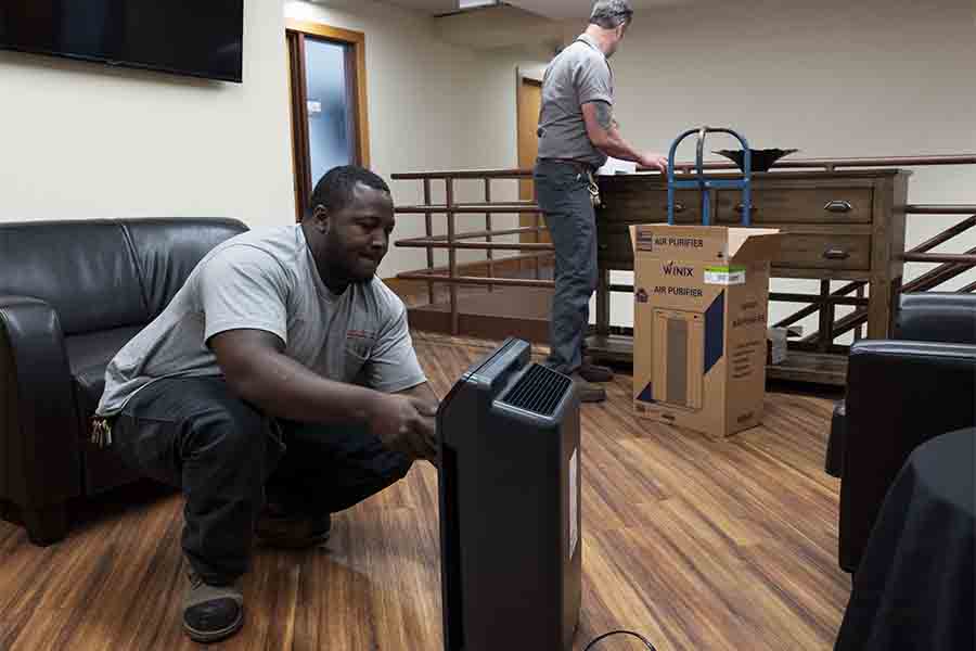Image of two laborers setting up air purifiers in Baker Hall