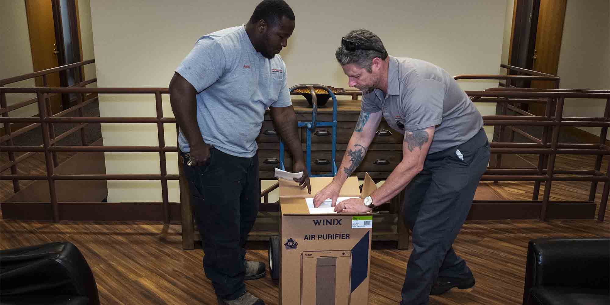 Image of laborers indoors opening an air purifier box