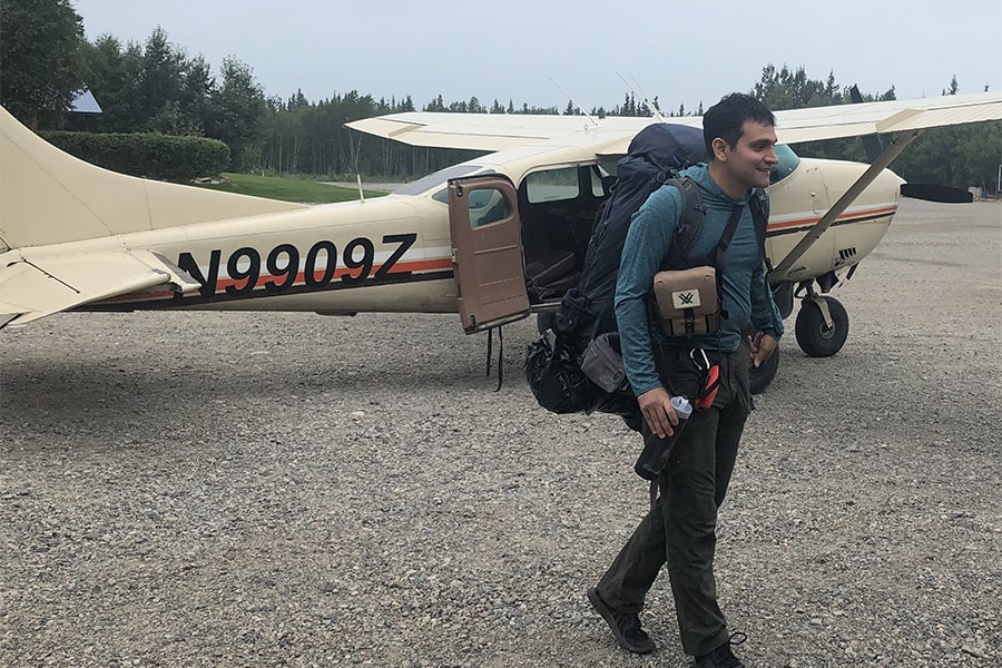 image of Azarakhsh Keipour wearing a backpack and walking away from a small airplane