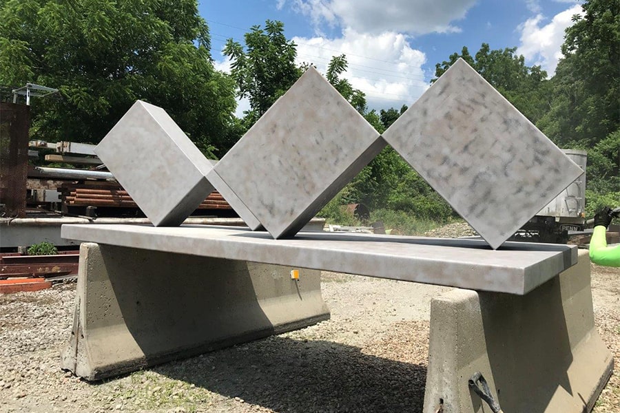 bare sculpture with blue sky, clouds, trees in background