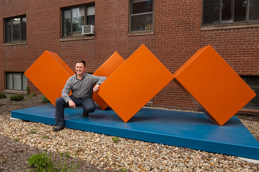 Chris Deely in front of finished orange sculpture