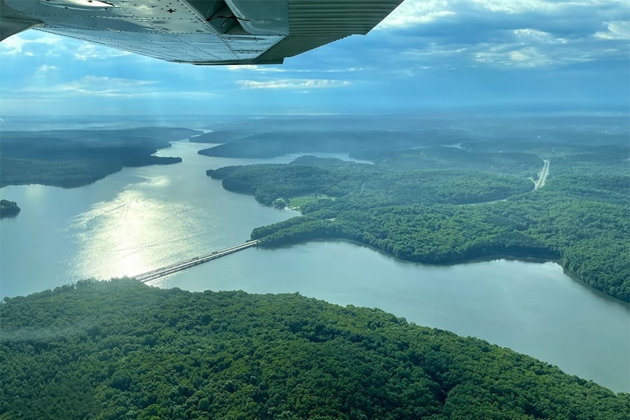 view of river and trees on land from plane on sunny day