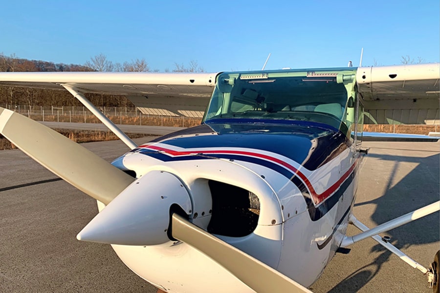 front of small plane sitting on tarmac on sunny day