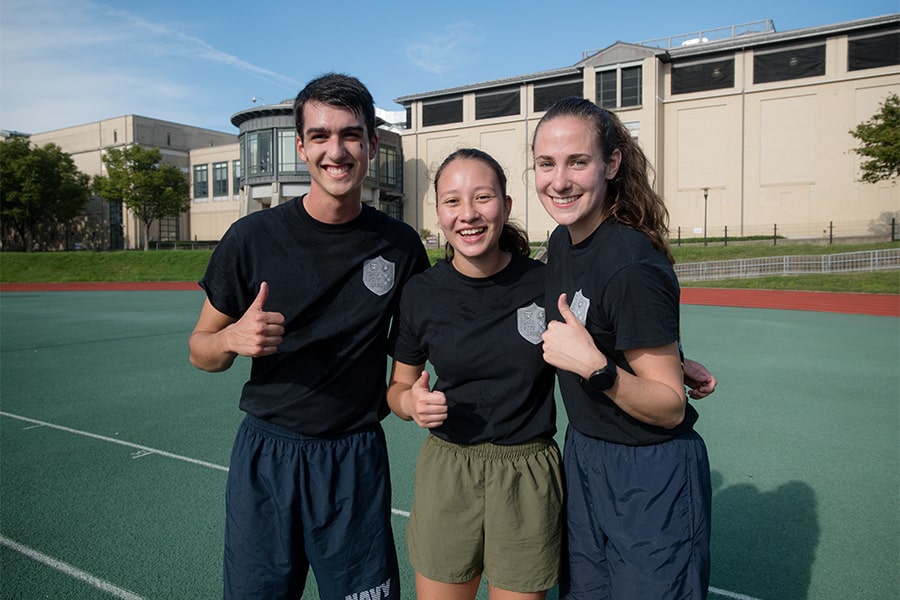 three midshipmen give the thumbs up sign