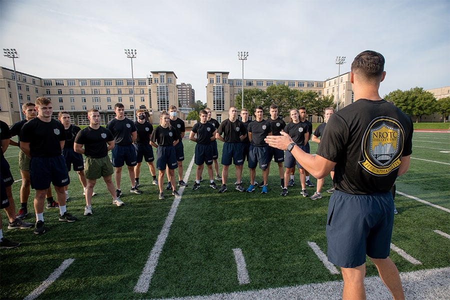 midshipmen listening to someone speak on the field at Gesling Stadium