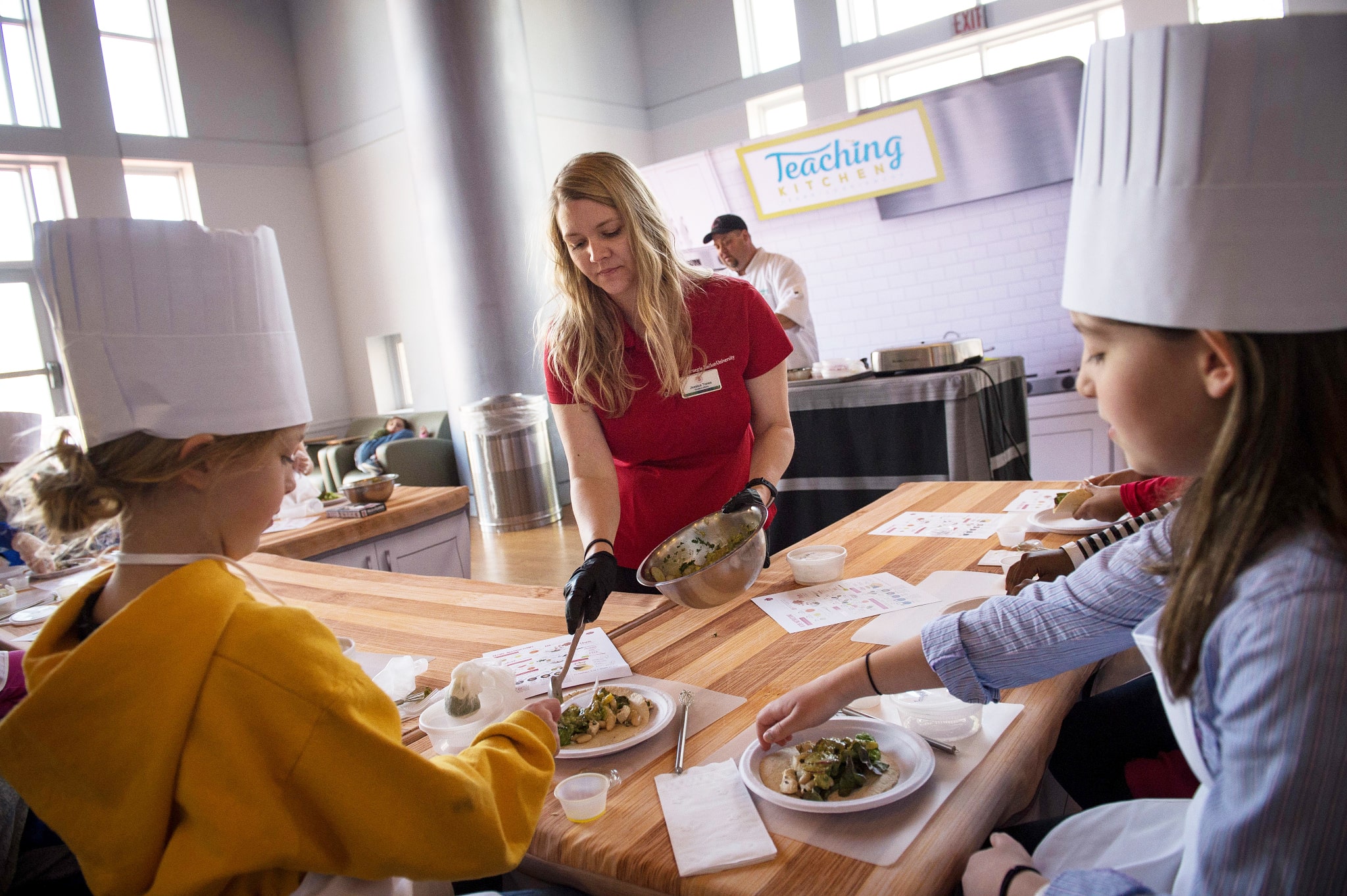 Jessica Tones serving food to kids during a Take Our Children to Work Day kitchen session