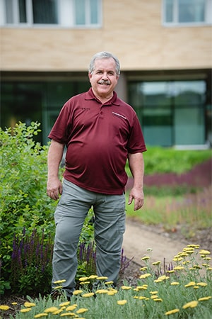 David Wessell standing with yellow flowers growing in front