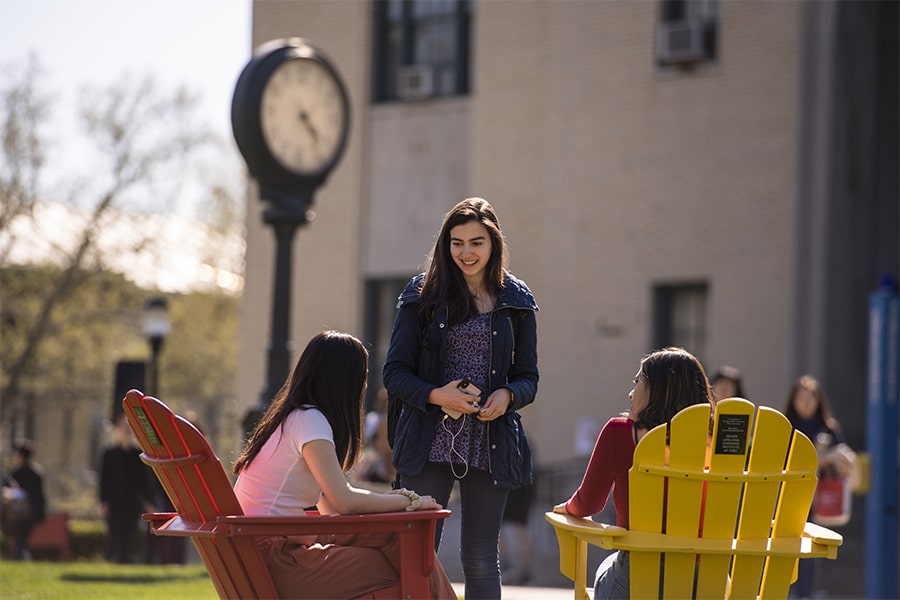 Girl talking to seated listeners in front of clock on Cut