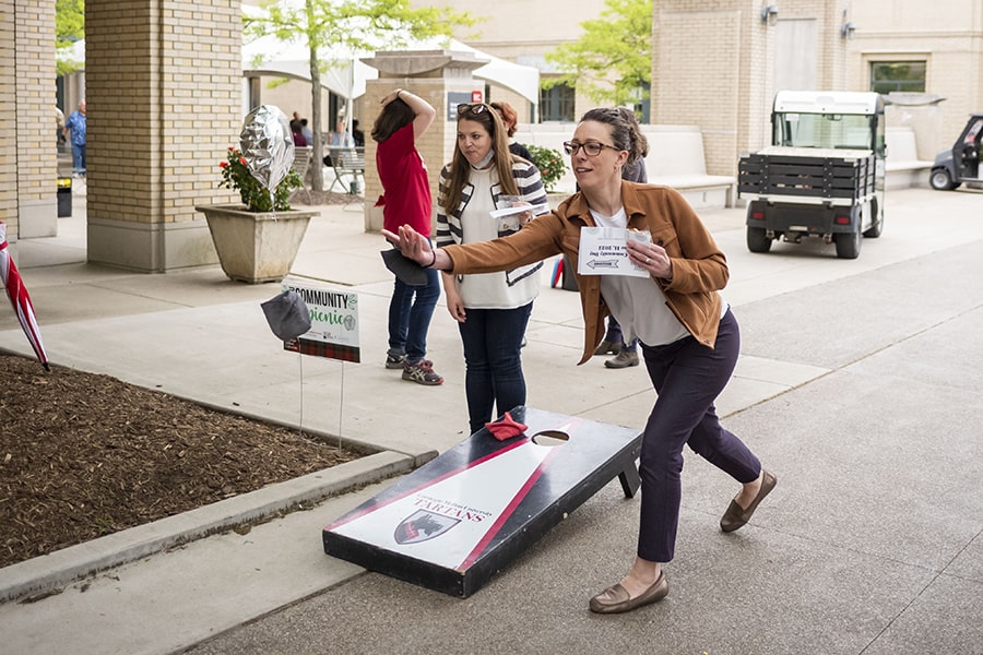 staff play cornhole at the picnic