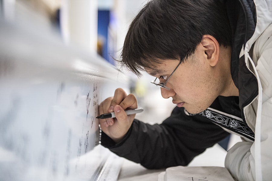 a student signs a steel beam for Ansys Hall