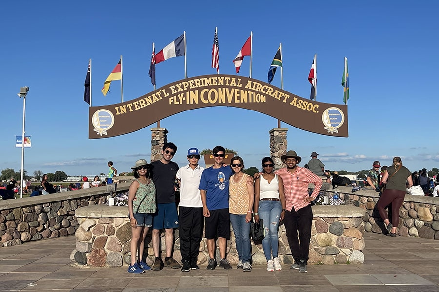 group photo of flying club members in front of EAA arch