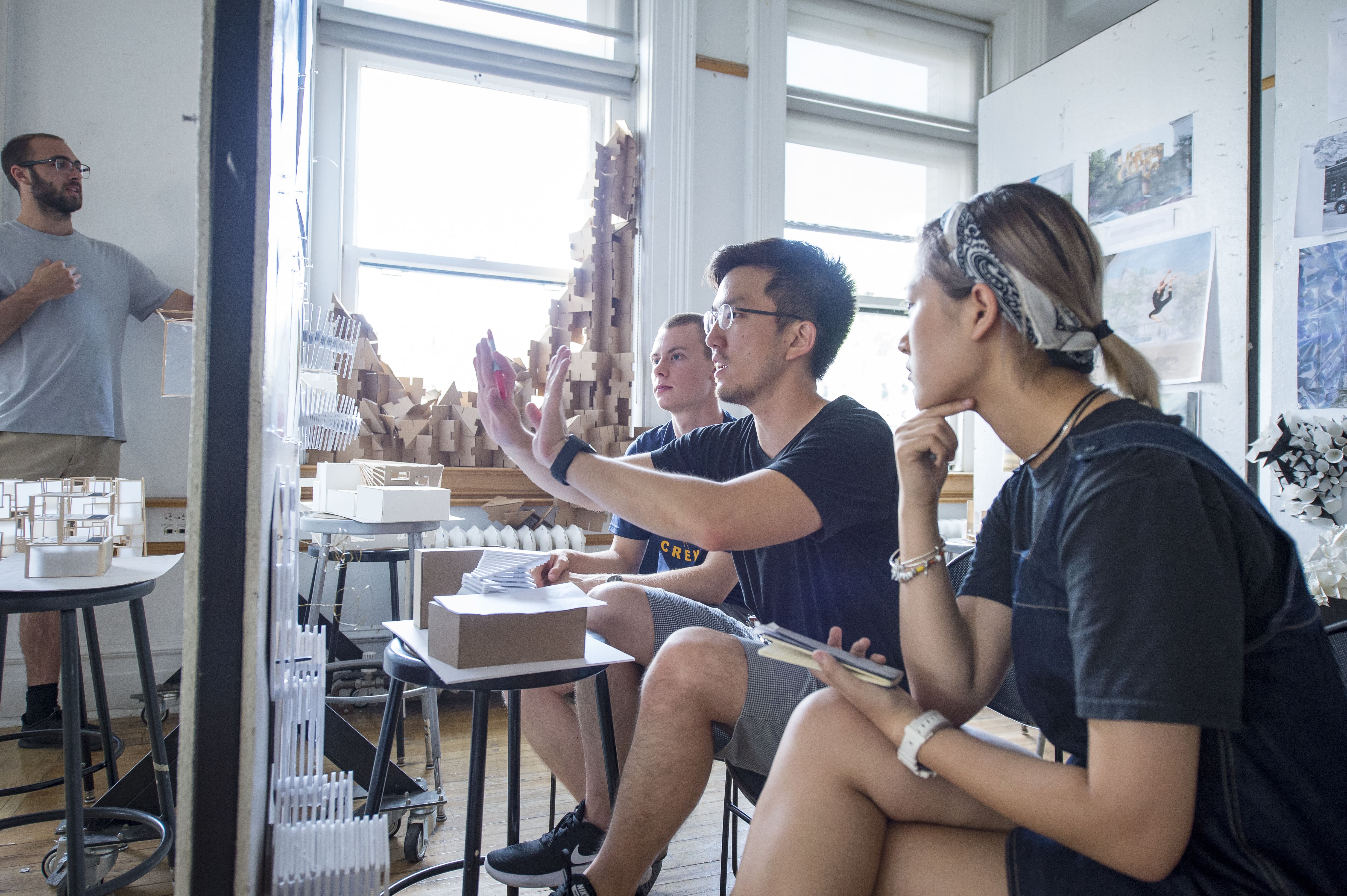 Three architecture students sitting and discussing their work