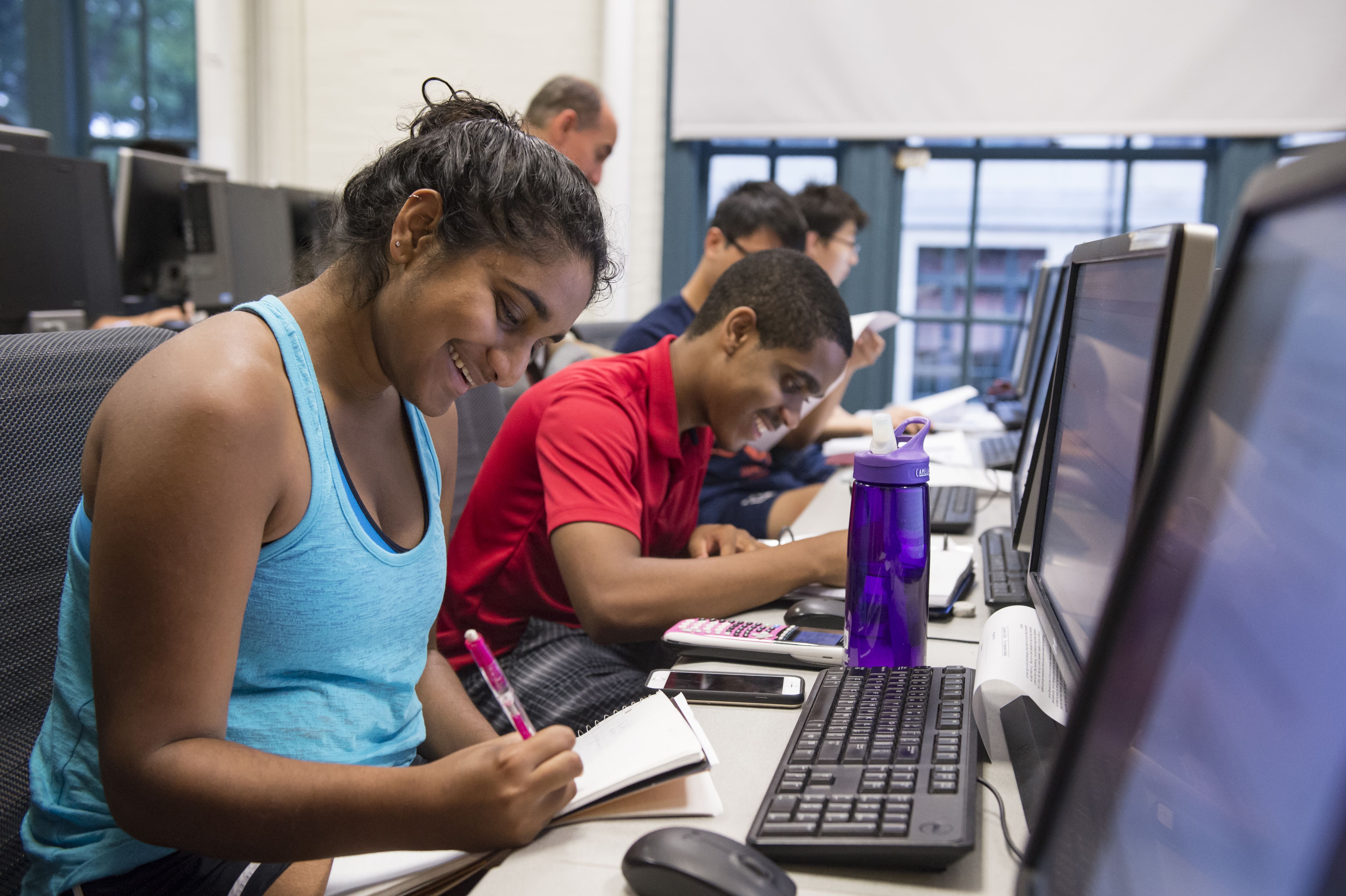 Pre-College students at computers, taking notes.