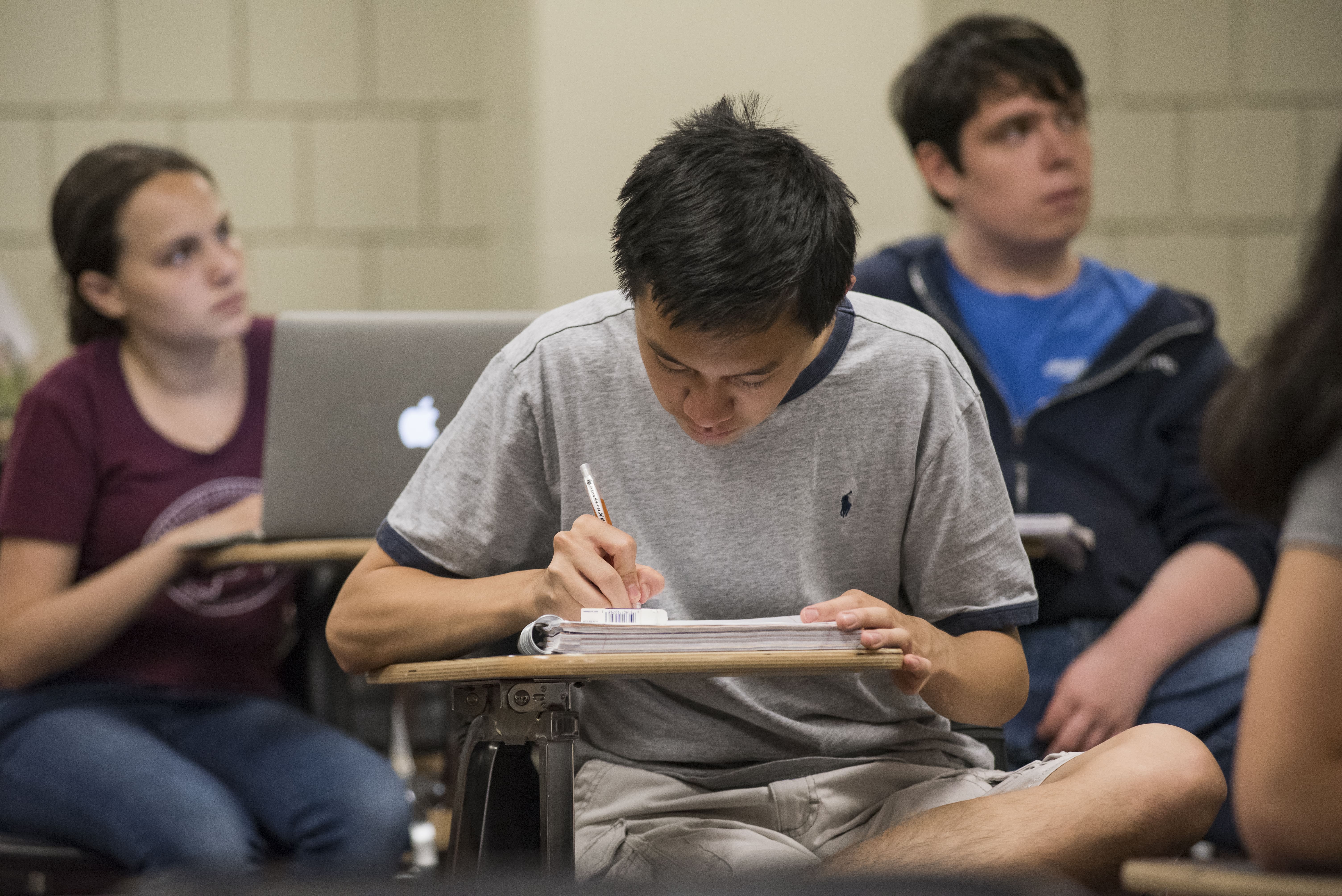 Pre-College student at desk taking notes.