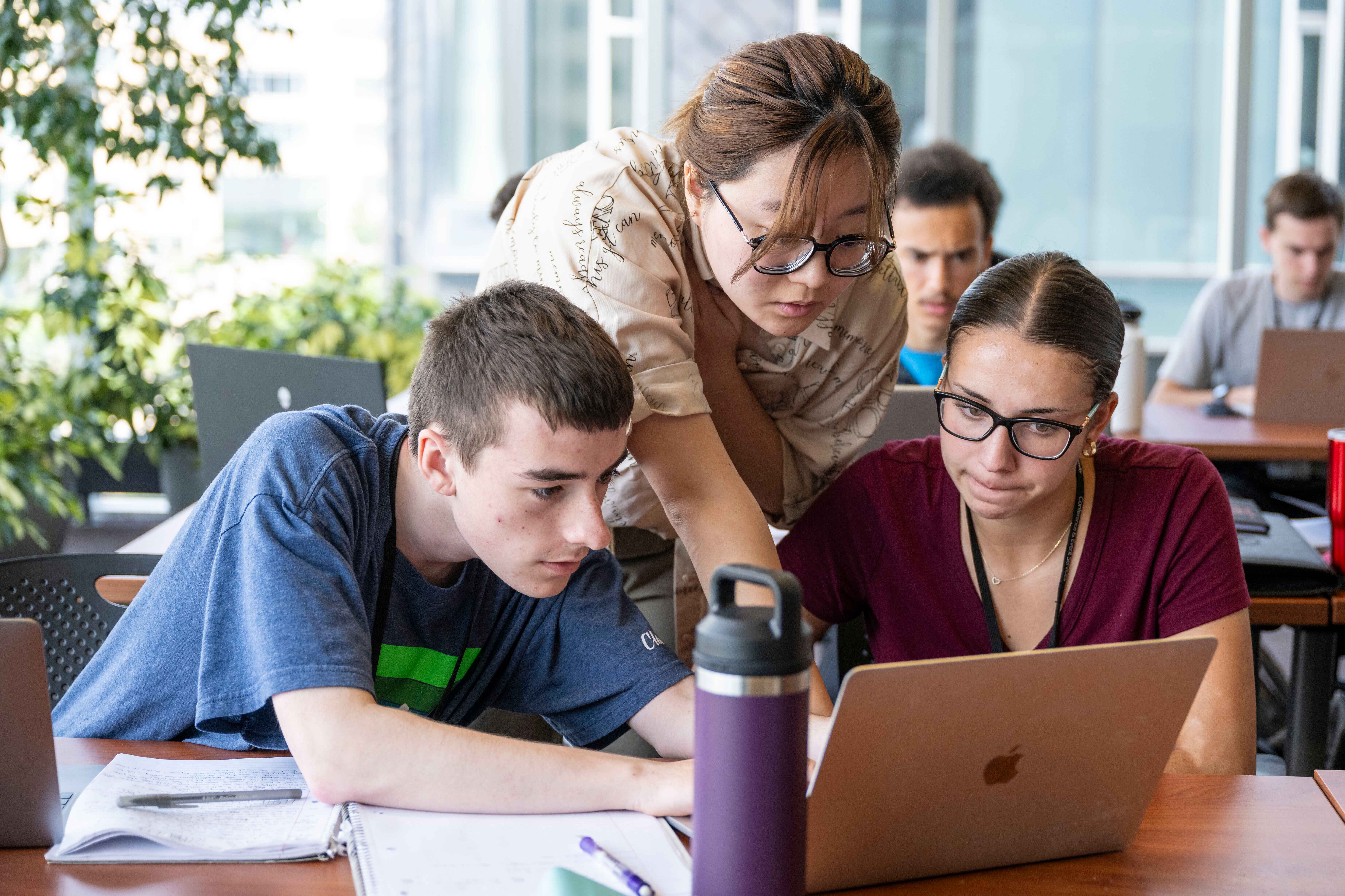 Students consulting a laptop screen in the classroom.