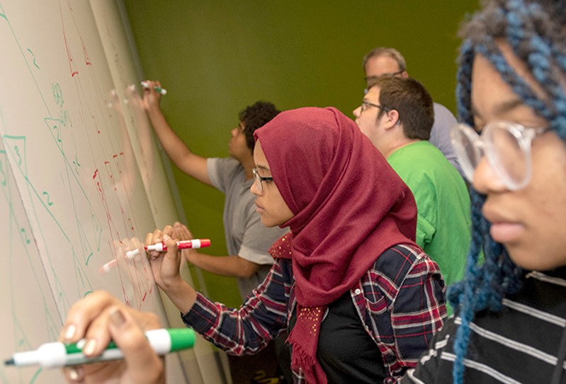 CSS students working together at a whiteboard.