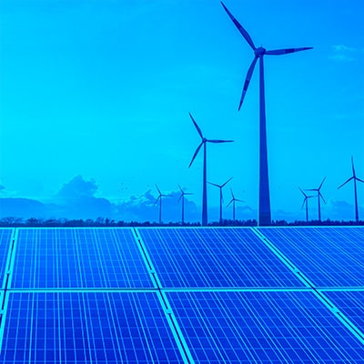 Solar panels in the foreground, with windmills in the background.