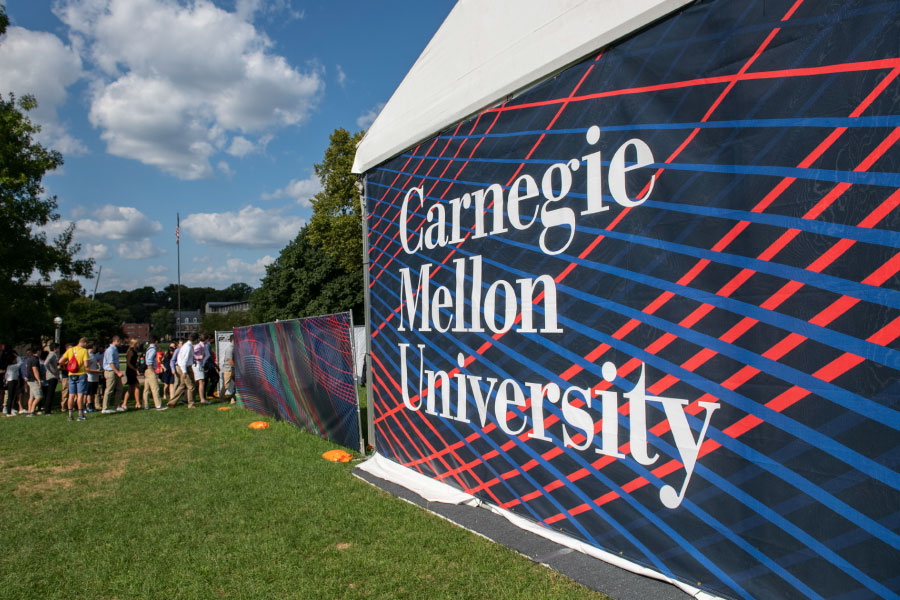 Tent with CMU Signage on campus and students lining up to enter the tent