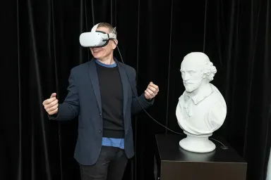 A person in a VR headset beside a bust of Shakespeare