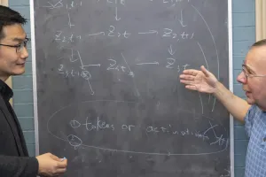 The Department of Philosophy's Kun Zhang (left) and Peter Spirtes (right) pictured in front of a chalkboard.