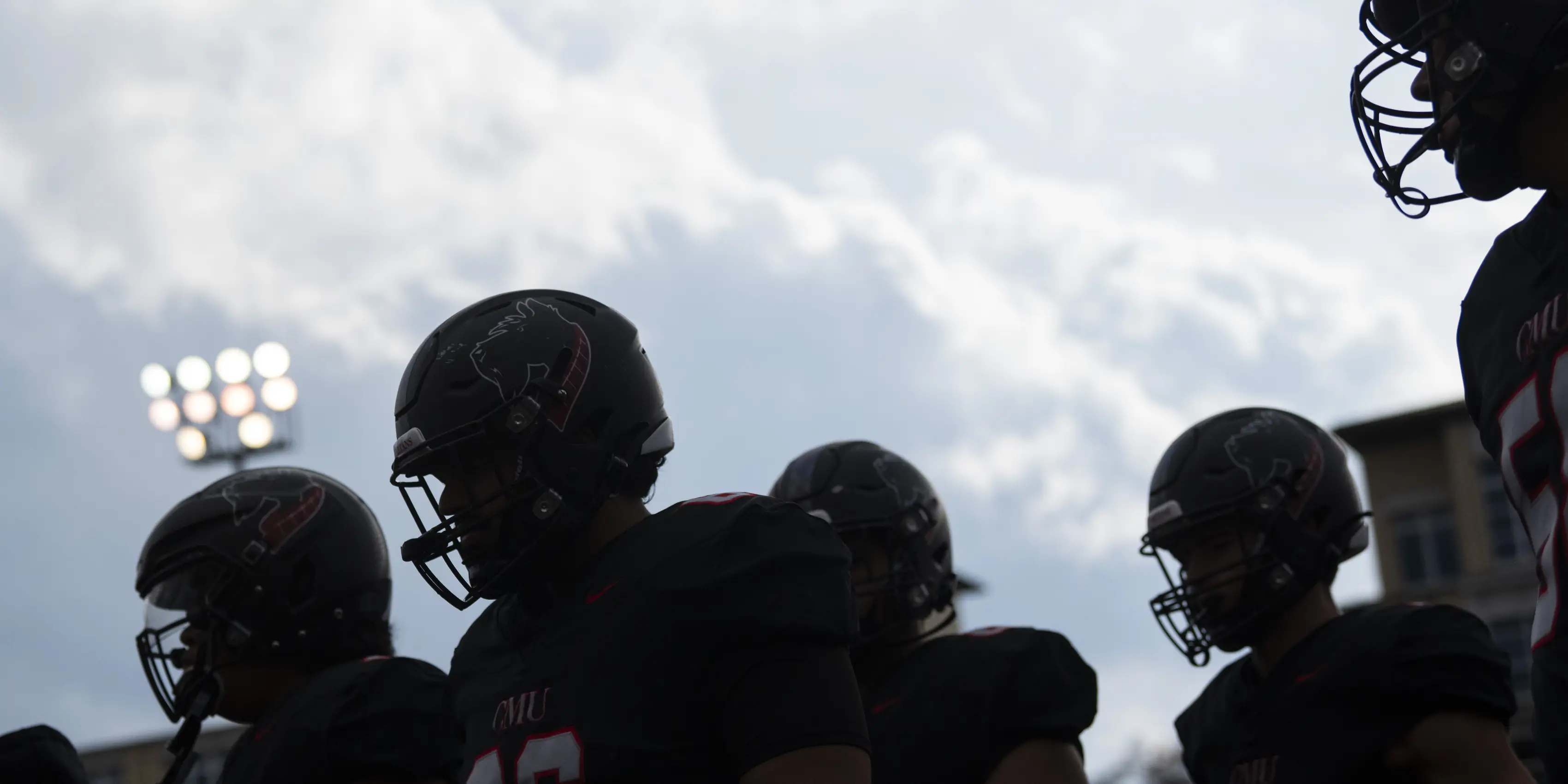 Football player silhouettes against a cloudy sky