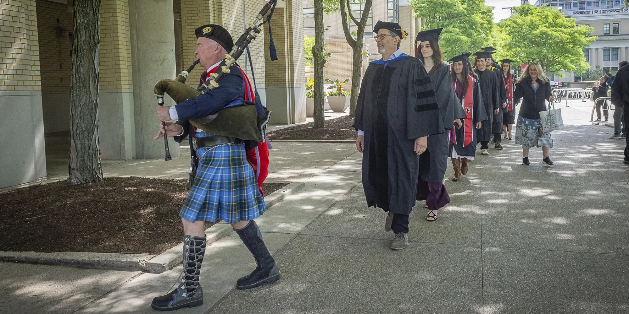 Richard Scheines and PBK inductees in regalia follow a bagpiper to their ceremony