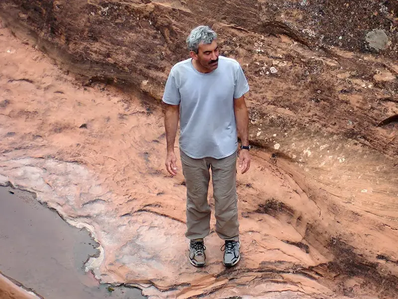 George Loewenstein standing on rocks near a stream