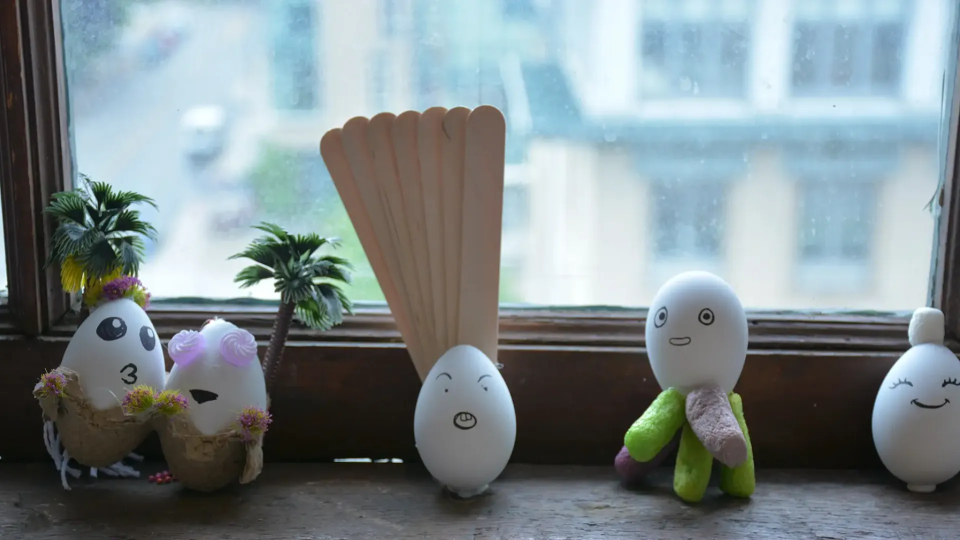 Eggs with faces painted on them lined up on a windowsill