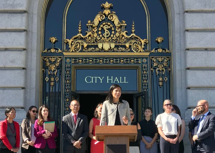 Breanna Zwart speaking from a podium in front of a City Hall building