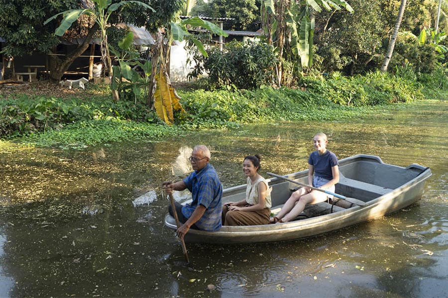 Phaw Pheeyin rows architecture students past a village compound in Thailand, sharing details on the upkeep of the canal systems by locals through yearly dredging. (Tommy Yang, 2020)