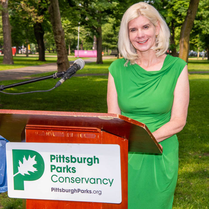 Catherine Qureshi speaking from a podium in a park
