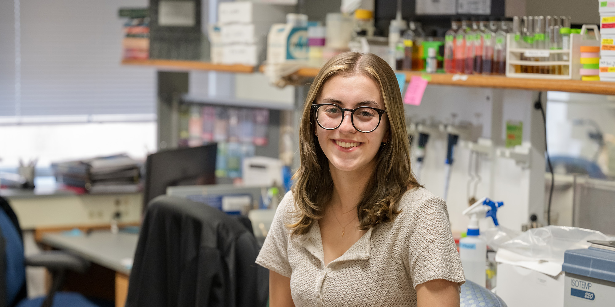 Anna Cappella smiling, sitting in a chemistry lab.