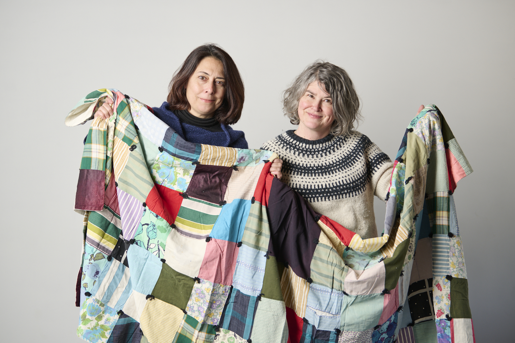 Two women holding up a quilt