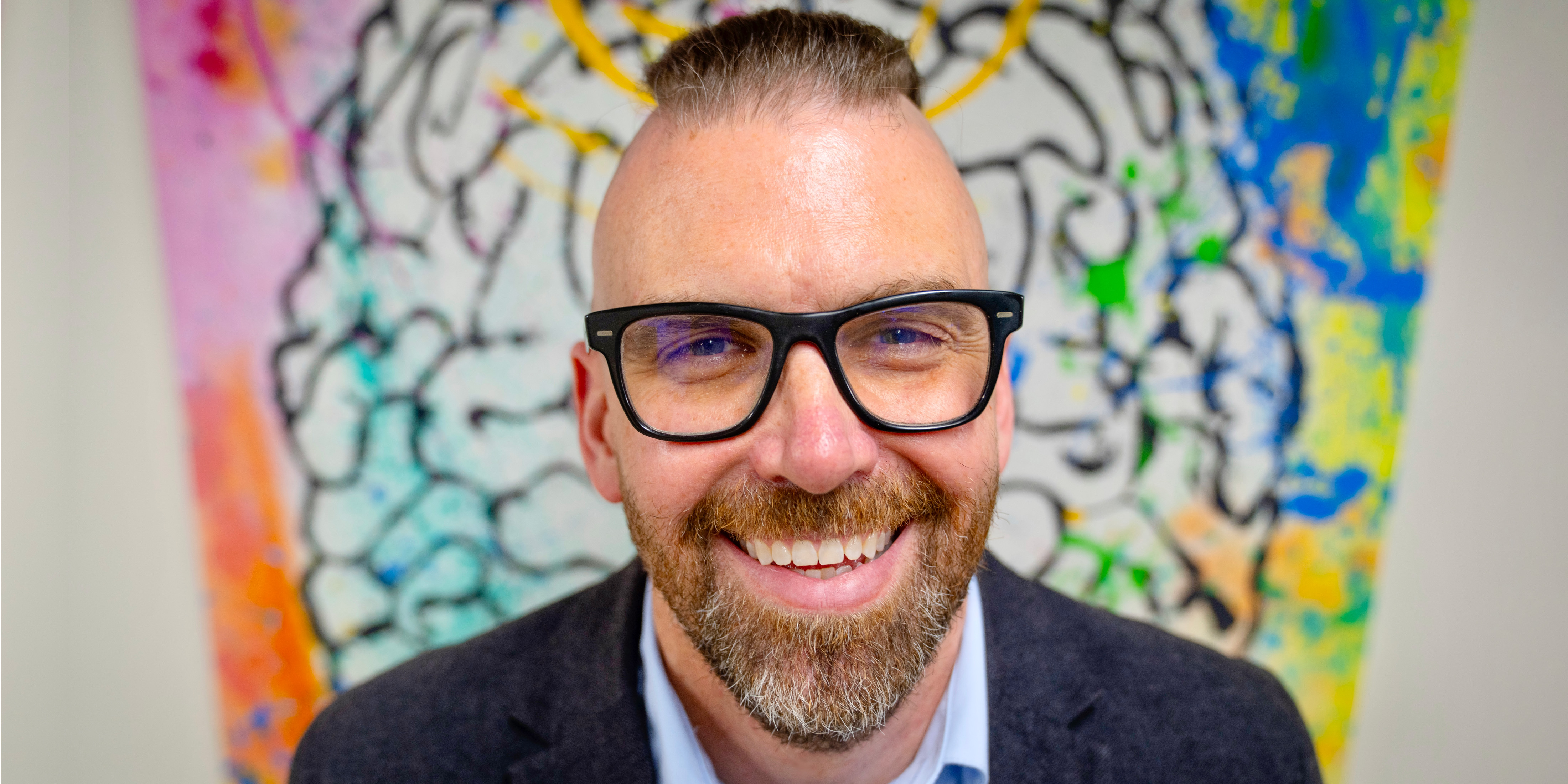 Image of man in front of a colorful painting.