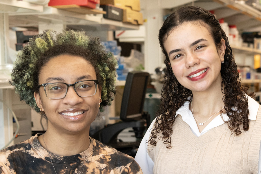Two smiling young female scientists posing in a lab.