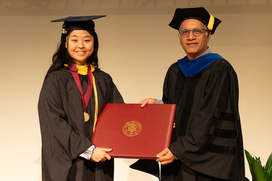 Female student receiving her diploma from department head.