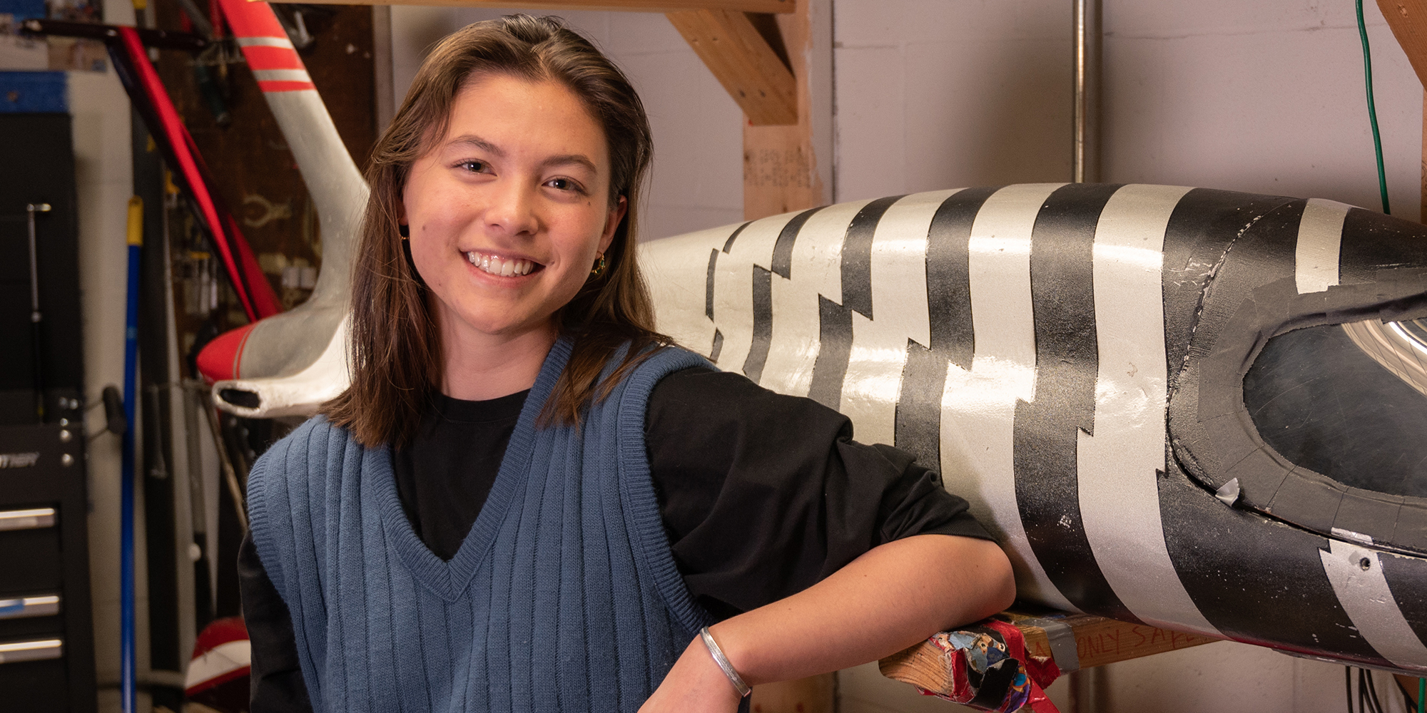 Smiling young student posing indoors in front of a buggy.