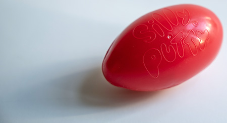 A red, egg-shaped plastic container labeled "Silly Putty".