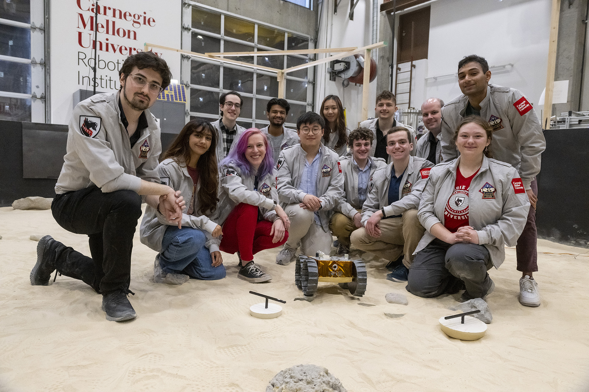 Members of the Iris lunar rover team, including Sonja Michaluk, kneeling together and smiling while posing for a group photo.