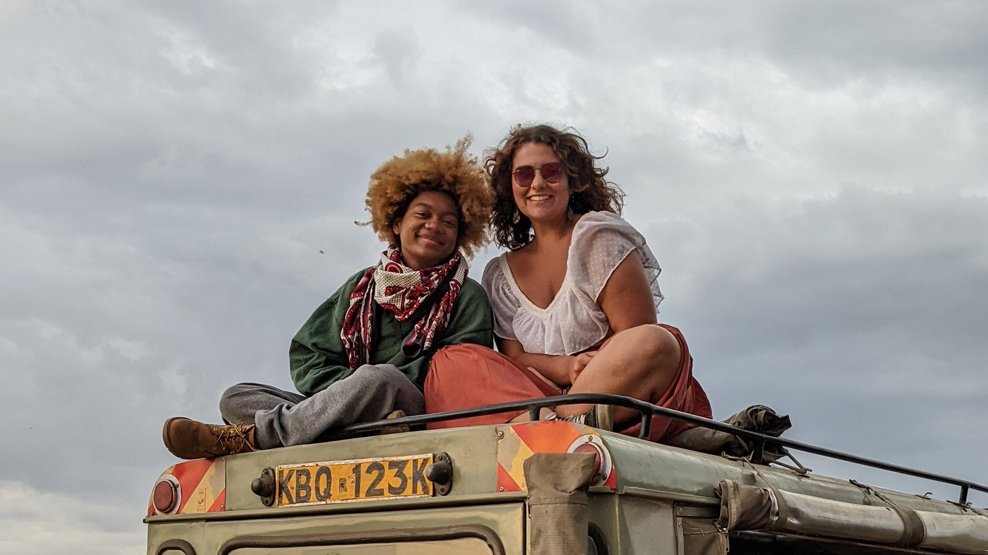 Eric Morales-Armstrong and Isabel Brum sit on top of a vehicle in the Masaai Mara.